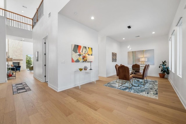 interior space featuring a stone fireplace, light hardwood / wood-style floors, and a high ceiling