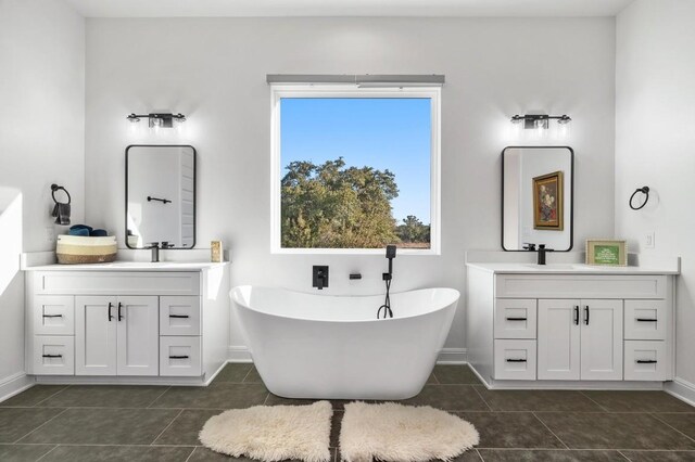 7224 Getaway Dr, Jonestown, TX 78645 - full bathroom with two vanities, tile patterned floors, a freestanding bath, and baseboards