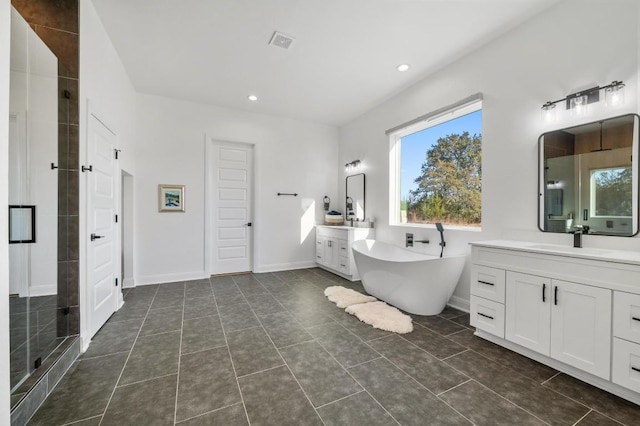 7224 Getaway Dr, Jonestown, TX 78645 - full bath with two vanities, a freestanding tub, a stall shower, tile patterned floors, and recessed lighting