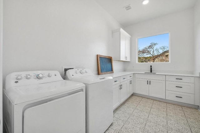 washroom with sink, light tile patterned floors, washing machine and dryer, and cabinets