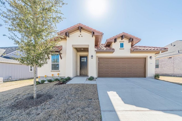 mediterranean / spanish-style home featuring a tile roof, a garage, driveway, and stucco siding