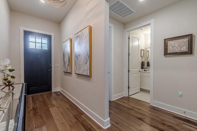 foyer entrance featuring wood finished floors, visible vents, and baseboards