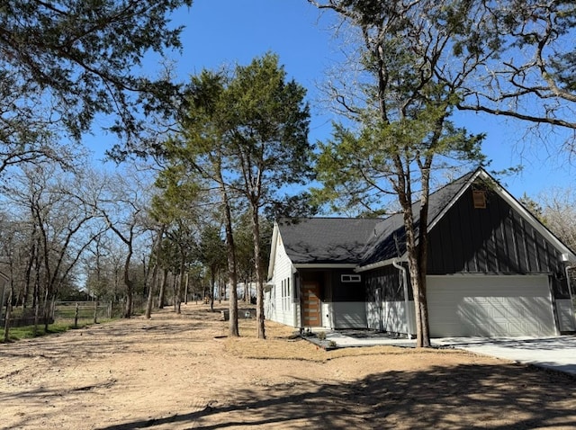 240 Shadow Oak Dr, Bastrop, TX 78602 - view of side of property with concrete driveway, board and batten siding, a garage, and roof with shingles