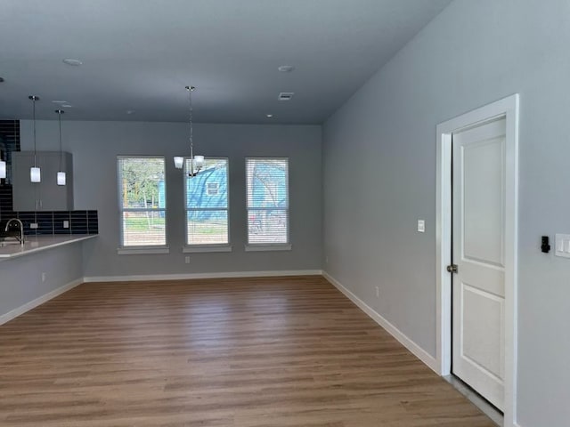 interior space featuring pendant lighting, sink, light hardwood / wood-style floors, and a notable chandelier