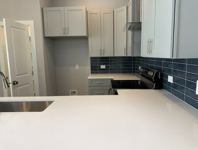 kitchen featuring sink, gray cabinetry, tasteful backsplash, range with electric stovetop, and wall chimney range hood