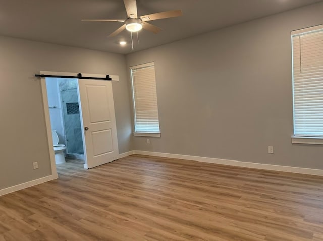 240 Shadow Oak Dr, Bastrop, TX 78602 - empty room with ceiling fan, baseboards, wood finished floors, and a barn door