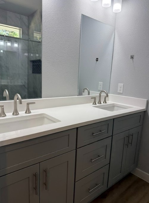 bathroom with hardwood / wood-style flooring, vanity, and a tile shower