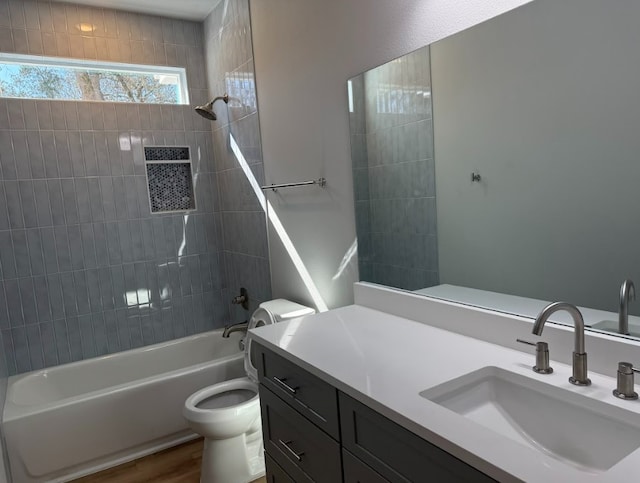 full bathroom with tiled shower / bath, wood-type flooring, vanity, and toilet