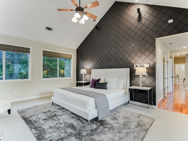 bedroom with vaulted ceiling, an accent wall, wallpapered walls, baseboards, and visible vents