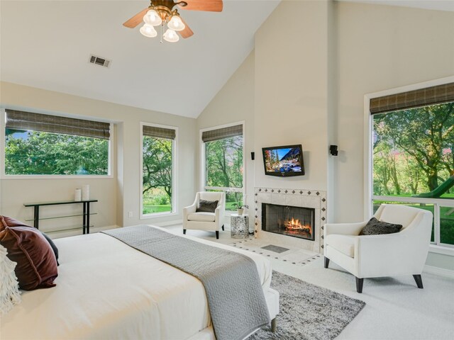 bedroom with a tiled fireplace, visible vents, high vaulted ceiling, and carpet floors