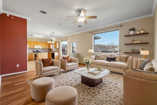 living room with ornamental molding, ceiling fan, and light wood-type flooring