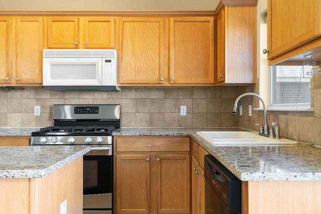 kitchen with stainless steel gas range, sink, dishwasher, light stone countertops, and backsplash