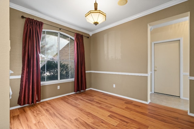 empty room with plenty of natural light, wood finished floors, baseboards, and ornamental molding