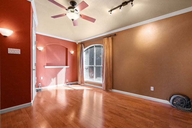 spare room featuring hardwood / wood-style flooring, crown molding, rail lighting, and ceiling fan