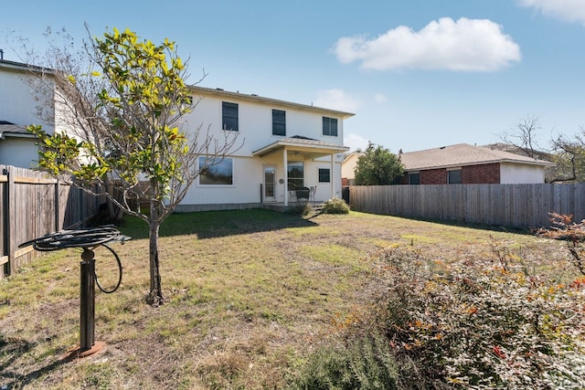 rear view of property featuring a fenced backyard, a lawn, and stucco siding