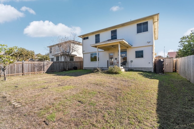 back of house featuring ceiling fan, a yard, and a fenced backyard