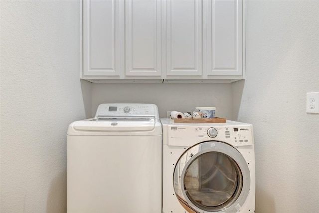 clothes washing area featuring cabinets and separate washer and dryer