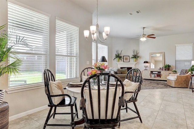 tiled dining space with ceiling fan with notable chandelier