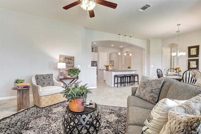 living room featuring sink and ceiling fan with notable chandelier