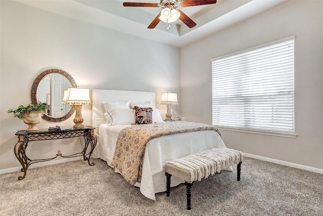 carpeted bedroom featuring ceiling fan and a tray ceiling