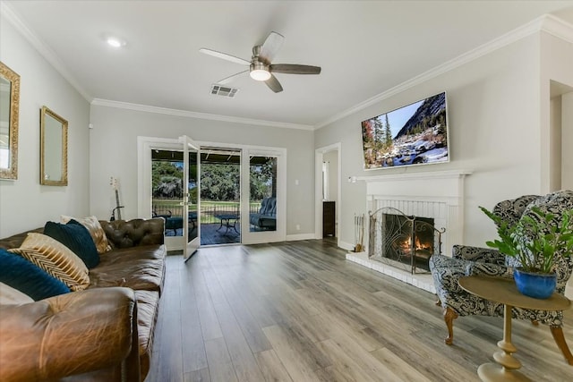 living room with ceiling fan, ornamental molding, a fireplace, and hardwood / wood-style floors