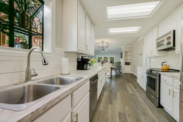 kitchen with white cabinetry, appliances with stainless steel finishes, sink, and light hardwood / wood-style flooring