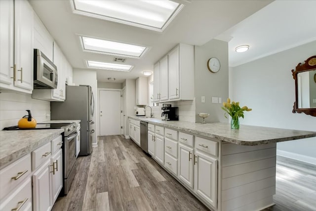 kitchen with a breakfast bar area, backsplash, stainless steel appliances, white cabinets, and kitchen peninsula