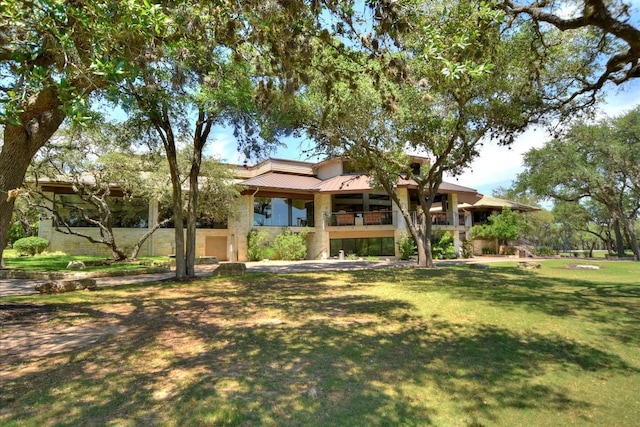 view of front of home with a balcony and a front lawn