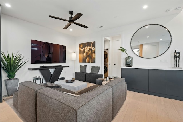 living room featuring light hardwood / wood-style floors, stacked washer and clothes dryer, and ceiling fan