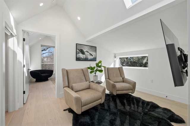 living area with a healthy amount of sunlight, light hardwood / wood-style floors, and a skylight