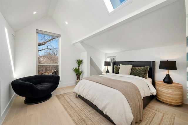 bedroom with lofted ceiling with skylight and light hardwood / wood-style floors