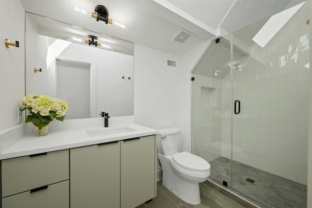 bathroom featuring vanity, a shower with shower door, and toilet