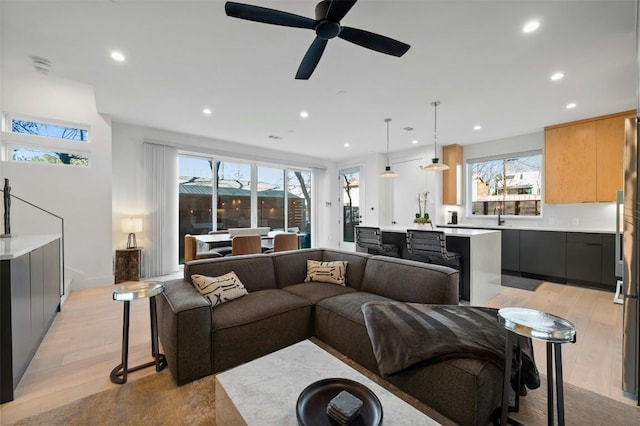 living room with ceiling fan, sink, and light hardwood / wood-style floors