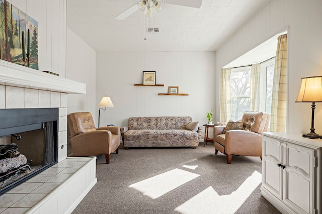 carpeted living room with a fireplace and ceiling fan