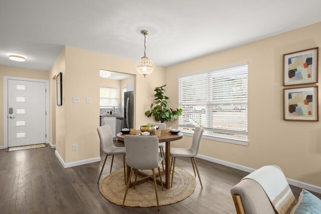 dining space with an inviting chandelier, sink, and dark wood-type flooring