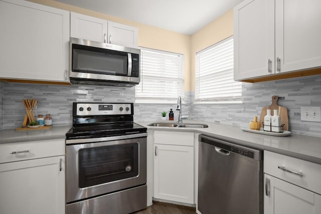 kitchen featuring stainless steel appliances, sink, decorative backsplash, and white cabinets