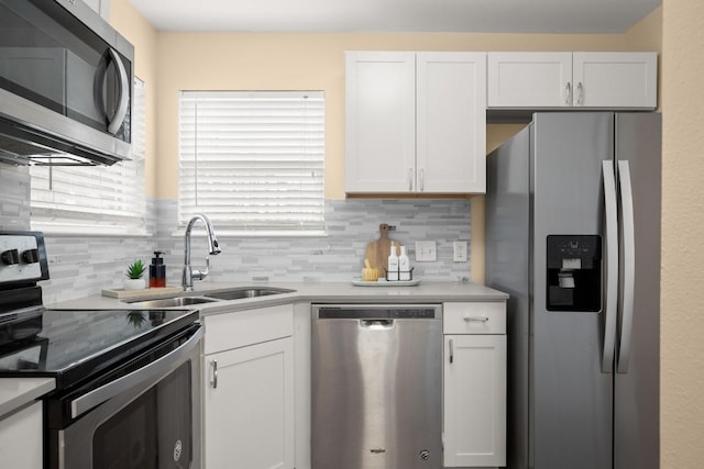 kitchen with appliances with stainless steel finishes, sink, white cabinets, and backsplash