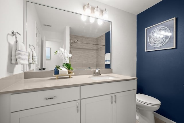 bathroom with vanity, toilet, and a tile shower