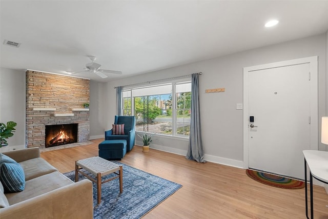 living room with ceiling fan, a fireplace, and light wood-type flooring