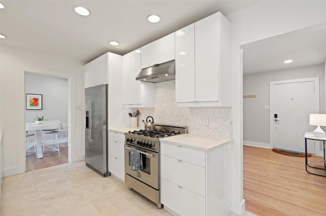 kitchen with high quality appliances, light hardwood / wood-style flooring, decorative backsplash, and white cabinets