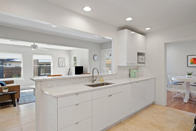 kitchen with white cabinetry, plenty of natural light, kitchen peninsula, and sink