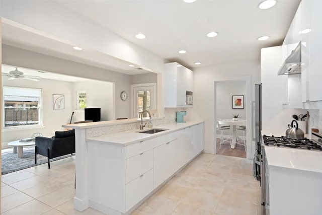 kitchen with white cabinetry, sink, stainless steel range with gas stovetop, and kitchen peninsula