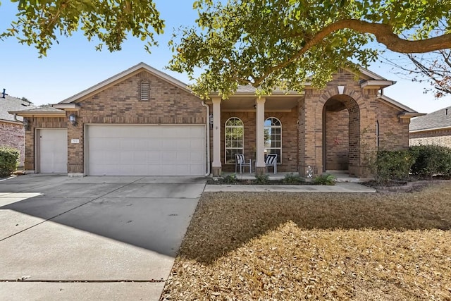 single story home with brick siding, a porch, concrete driveway, and a garage