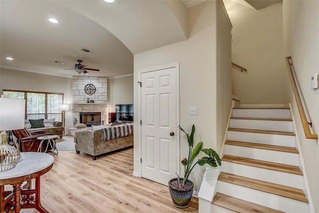 living room with crown molding, a fireplace, ceiling fan, and light hardwood / wood-style floors