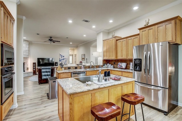 kitchen featuring sink, a kitchen breakfast bar, kitchen peninsula, stainless steel appliances, and crown molding