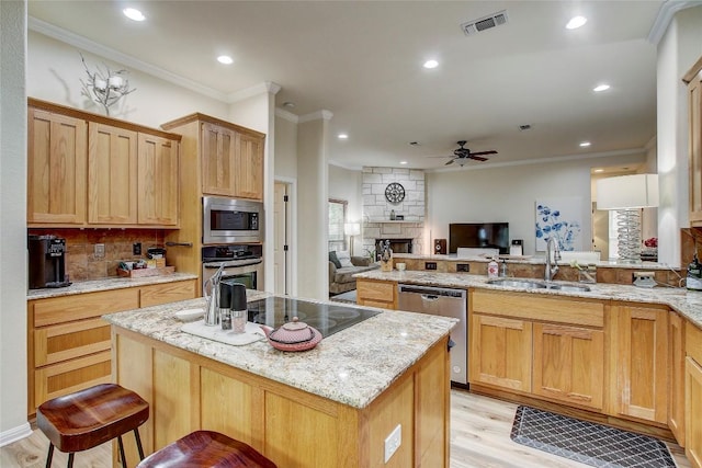 kitchen featuring sink, a kitchen breakfast bar, a kitchen island, stainless steel appliances, and light stone countertops