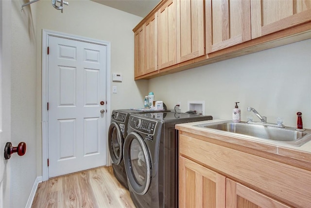 laundry room with cabinets, light hardwood / wood-style floors, sink, and washer and dryer