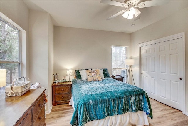 bedroom featuring multiple windows, a closet, ceiling fan, and light wood-type flooring