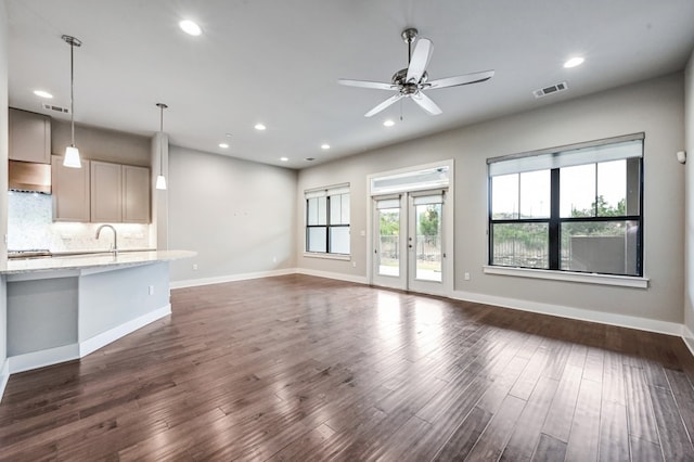 unfurnished living room featuring dark hardwood / wood-style flooring, sink, french doors, and ceiling fan