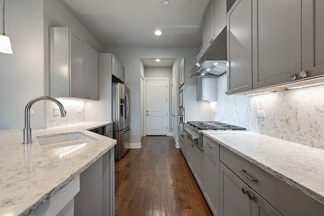 kitchen with gray cabinets, appliances with stainless steel finishes, decorative light fixtures, sink, and light stone counters